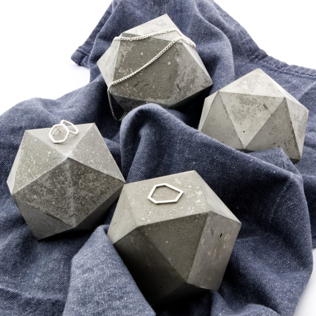 Eine grosse Bühne für feinen Schmuck. Geometrische Skulptur Props aus gealtertem Beton kontrastieren auf blauem Stoff und präsentieren den Schmuck. Geometrische Skulptur Props aus gealtertem Beton kontrastieren auf blauem Stoff und präsentieren den Schmuck.
