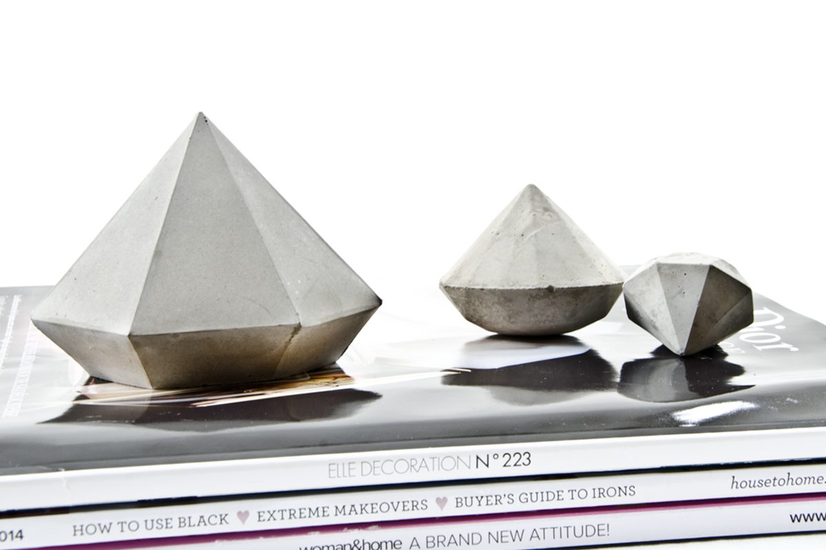 Drei Diamanten in hellem Beton in 3 verschieden Designs und Größen auf Magazinen.