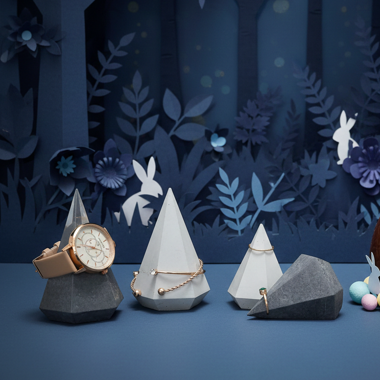 Diamant Armbandständer und Ringhalter mit Beispielschmuck und blauen Papierblumen im Hintergrund Diamant Armbandständer und Ringhalter mit Beispielschmuck und blauen Papierblumen im Hintergrund