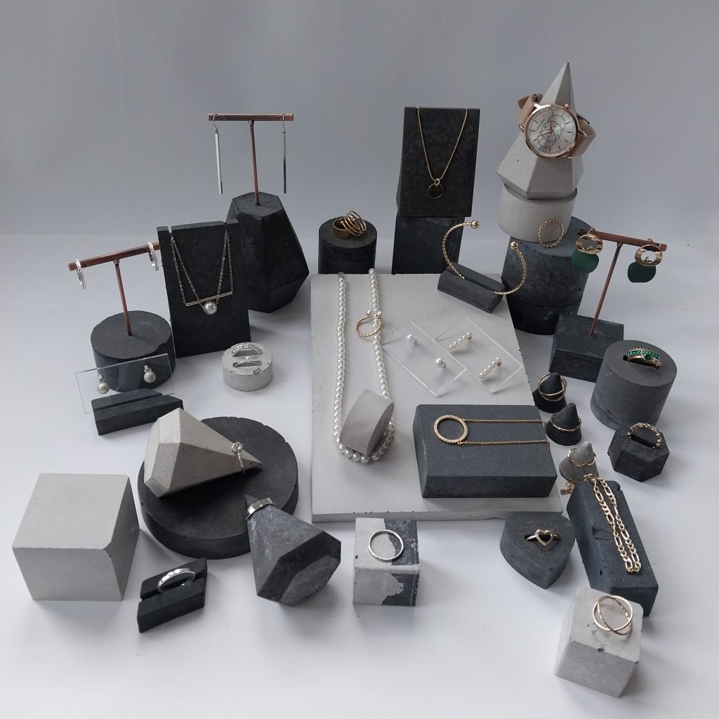 Heller und dunkler Beton in geometrischen Formen als Schmuckständer im Display Beispiel mit Schmuck