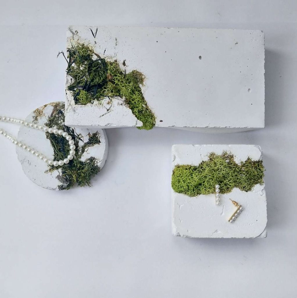 Weisser Beton mit grünem Moss in geometrischen Formen als Schmuckständer